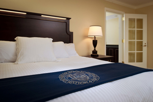 Morris Inn King Suite - A white linen bed with a wooden headboard fill the bedroom.